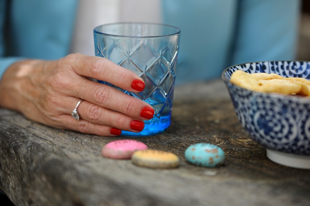 יד אוחזת בכוס זכוכית כחולה – רגע של שלווה, שקט ובחירה מודעת בגישת אמנות המסוגלות